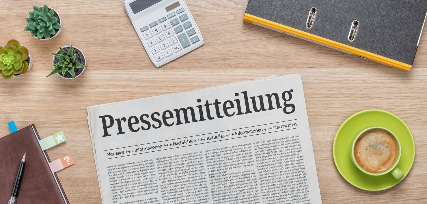 A newspaper on a desk with the headline Press Release in german – Pressemitteilung Eine Tageszeitung mit dem Titel Pressemitteilung