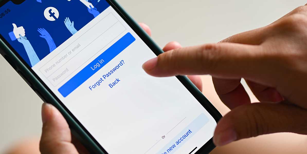 workshop-facebook Person hält Smartphone mit Login Startseite von Facebook